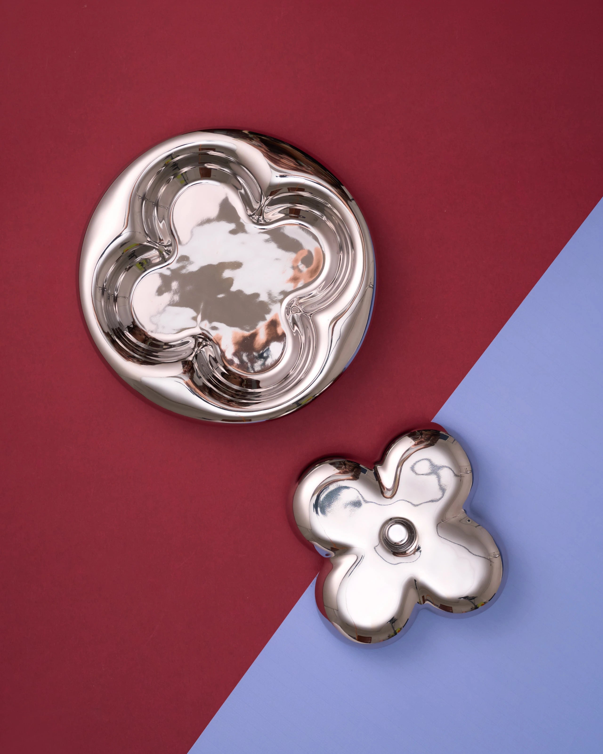 Two silver flower-shaped objects on a two-tone red and blue background